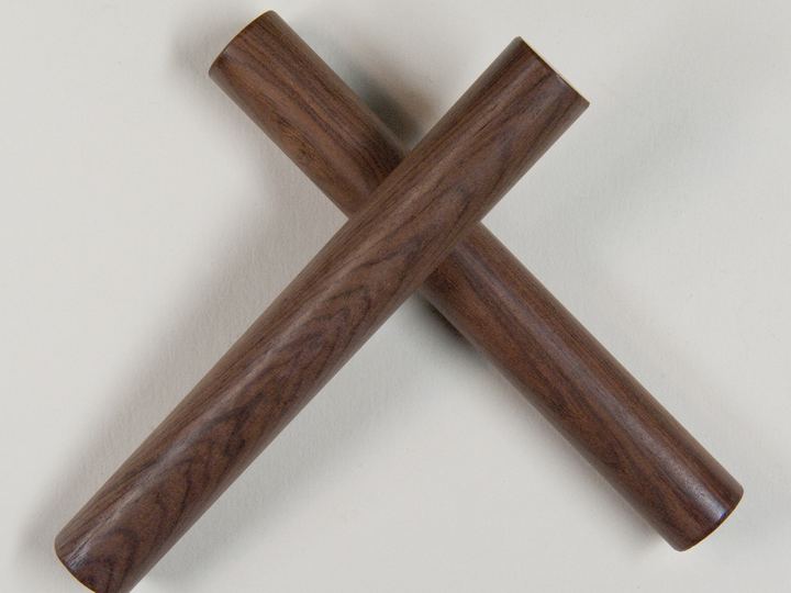 A pair of dark wooden claves crossed on a white background