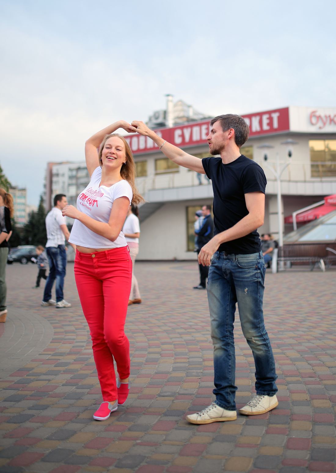A leader raises his partner's hand for a turn on a city square