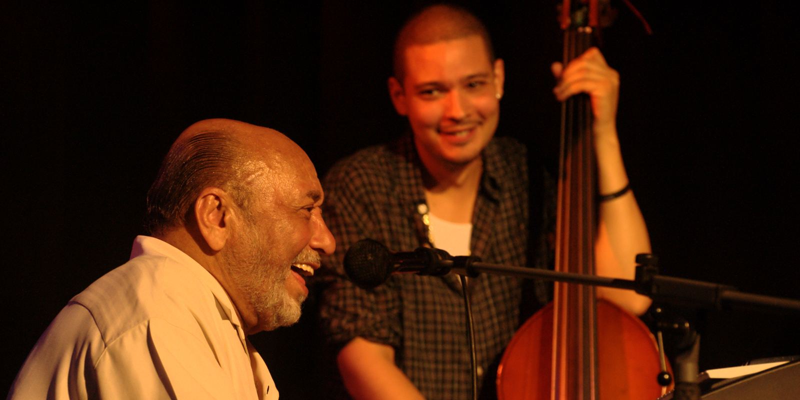 Eddie Palmieri playing piano on stage alongside a bassist